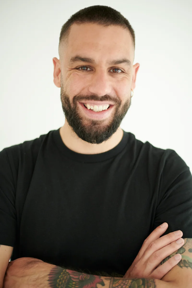 Antoine Andrieu souriant, en t-shirt noir, les bras croisés.